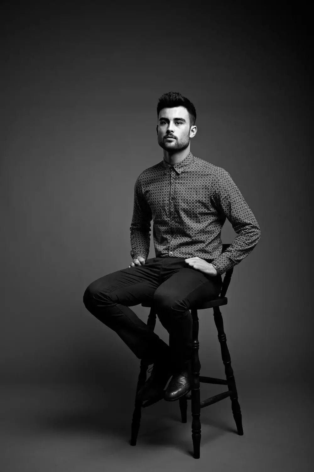 Man with a medium quiff sitting down on a chair