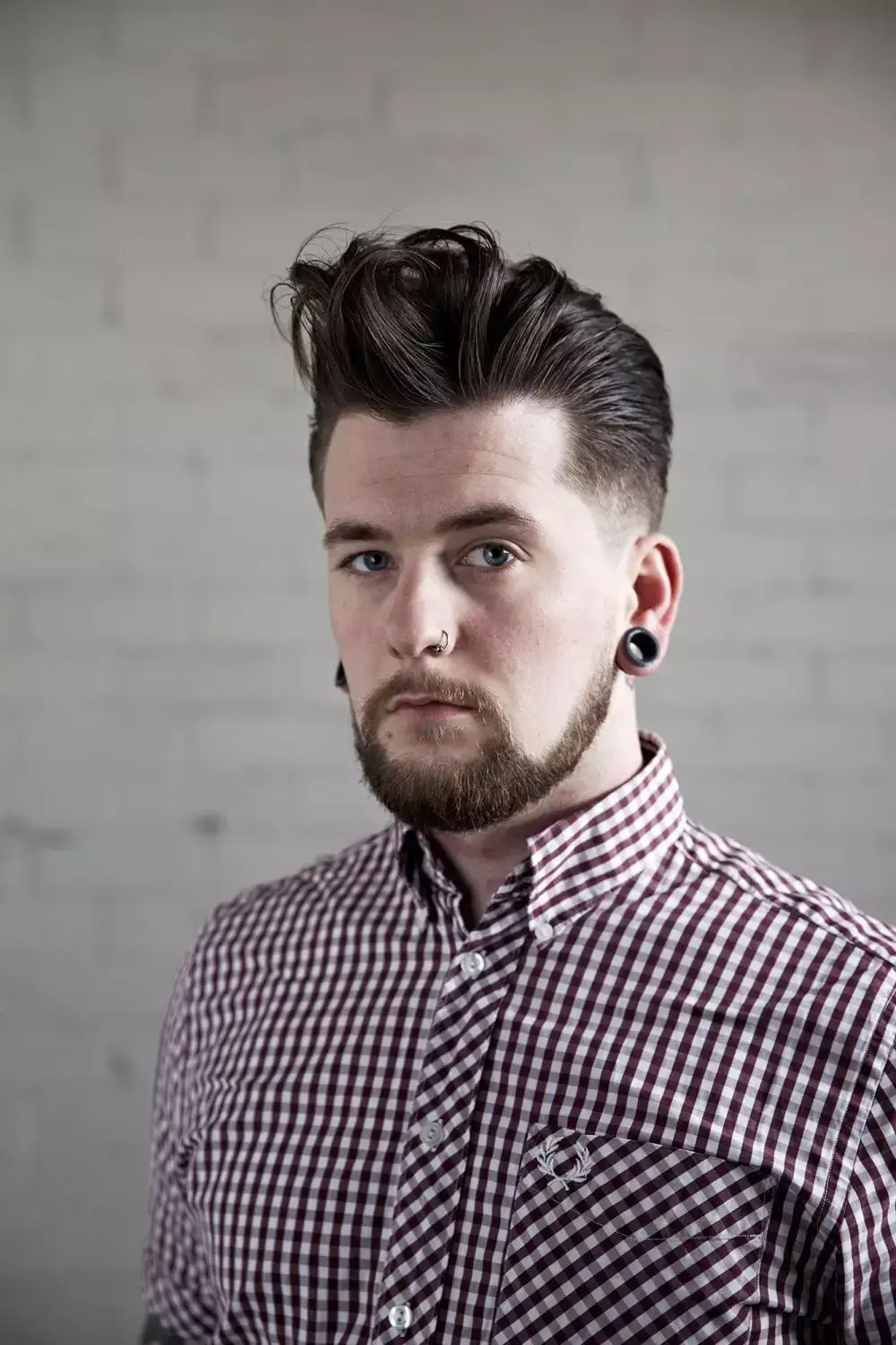 Man with large quiff with piercings, beard and checked shirt