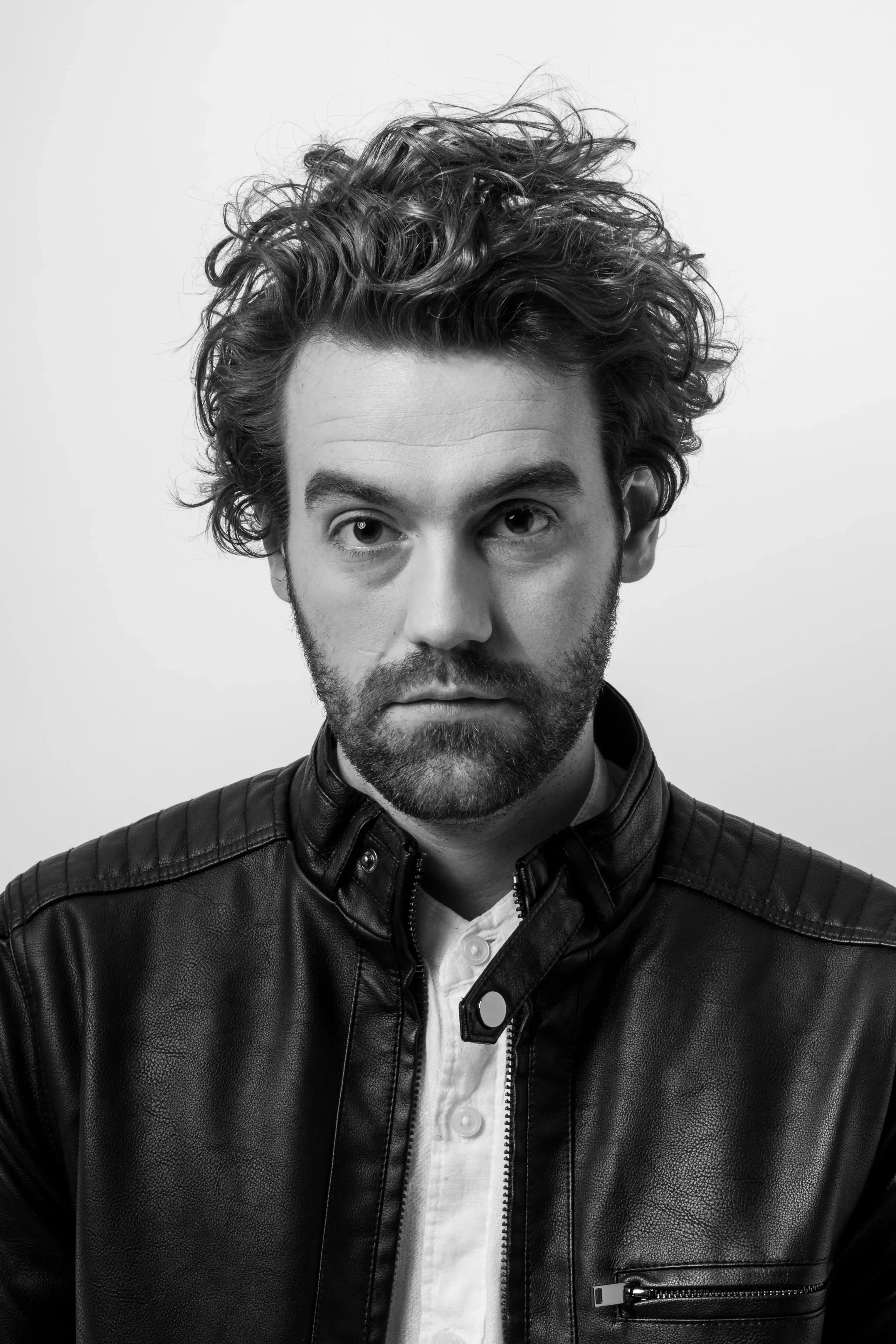 Man with wavy medium length hair with beard in black and white