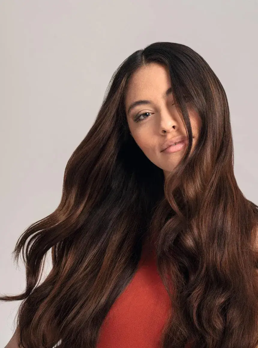 Woman with long brown wavy hair in red top